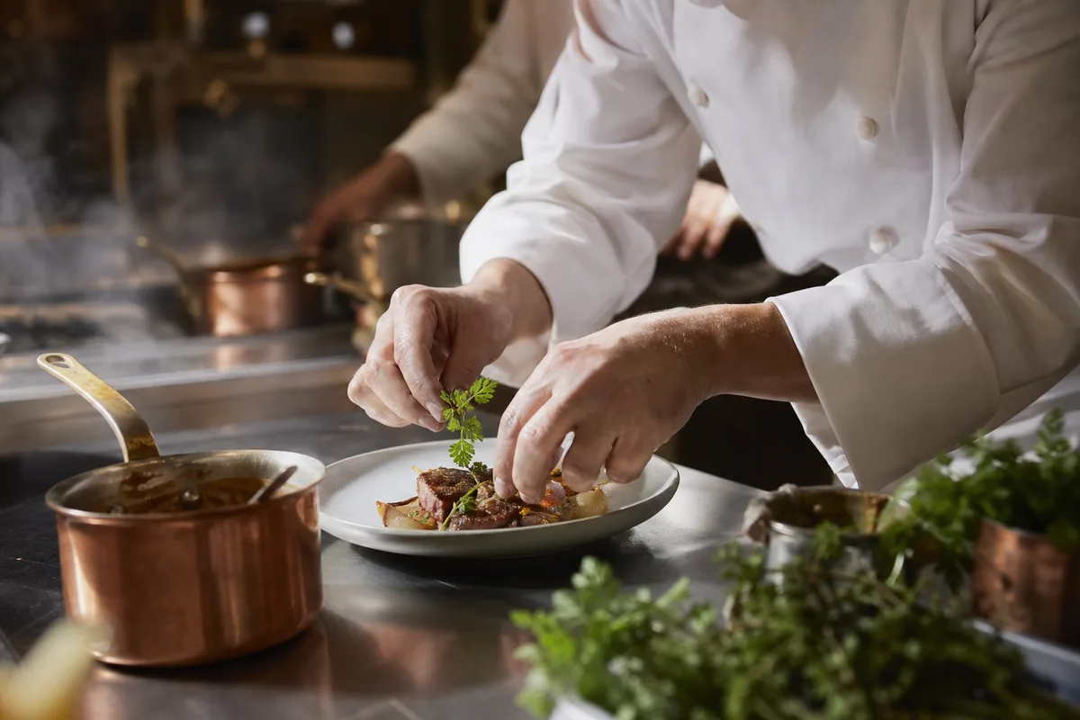 Commis dressant une assiette dans la cuisine d&rsquo;un petit restaurant traditionnel