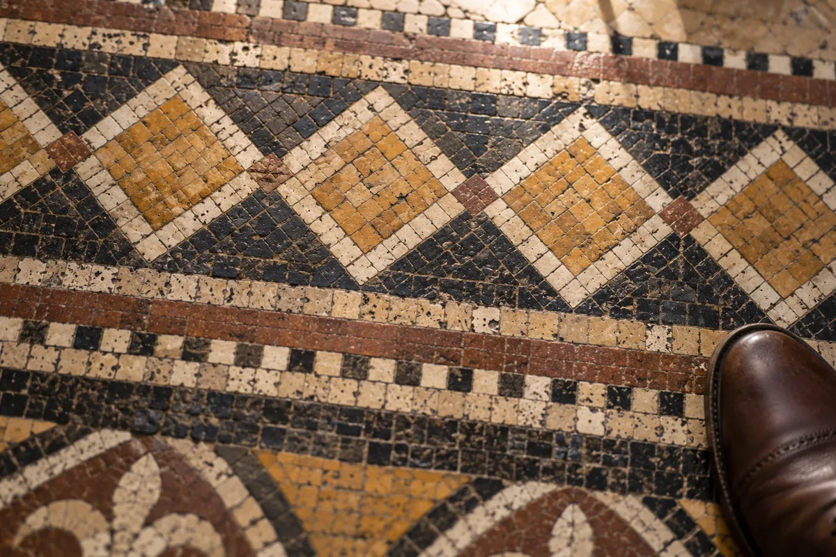 Sol en mosaïque ancienne à motifs géométriques dans une galerie couverte