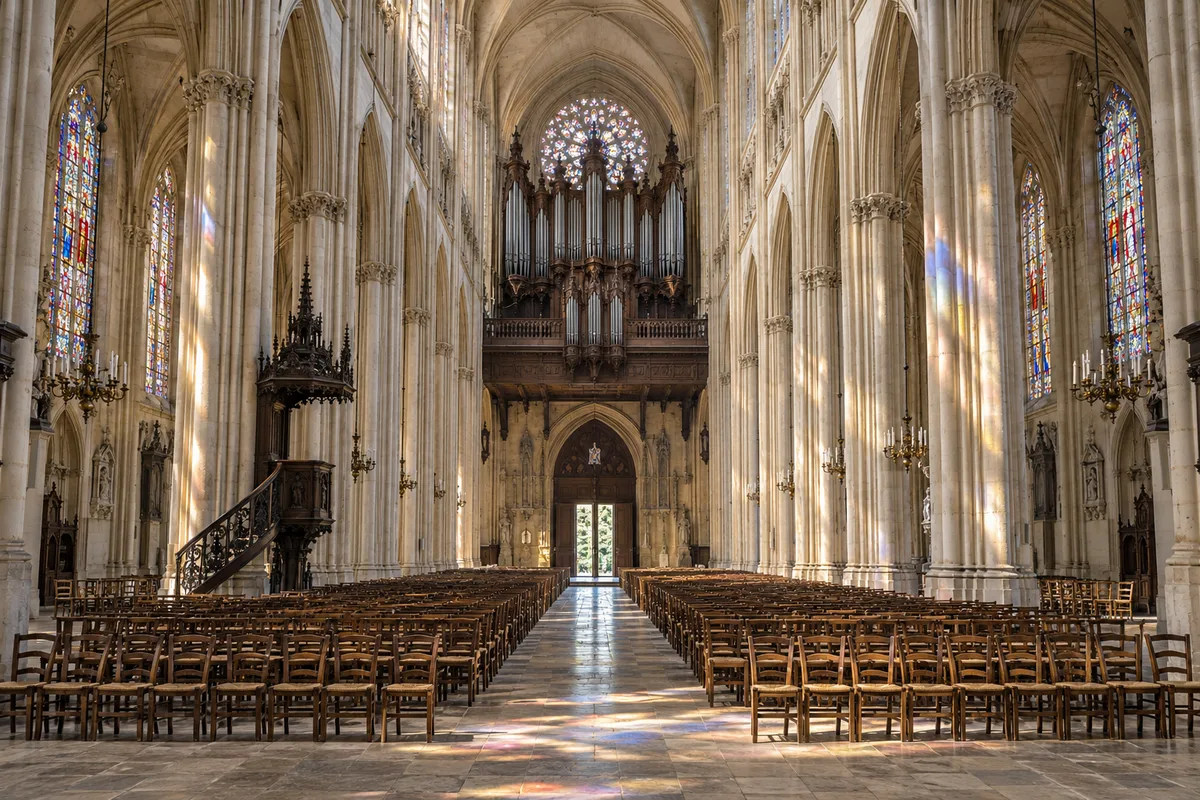 Nef d’une église gothique baignée de lumière avec un orgue au fond